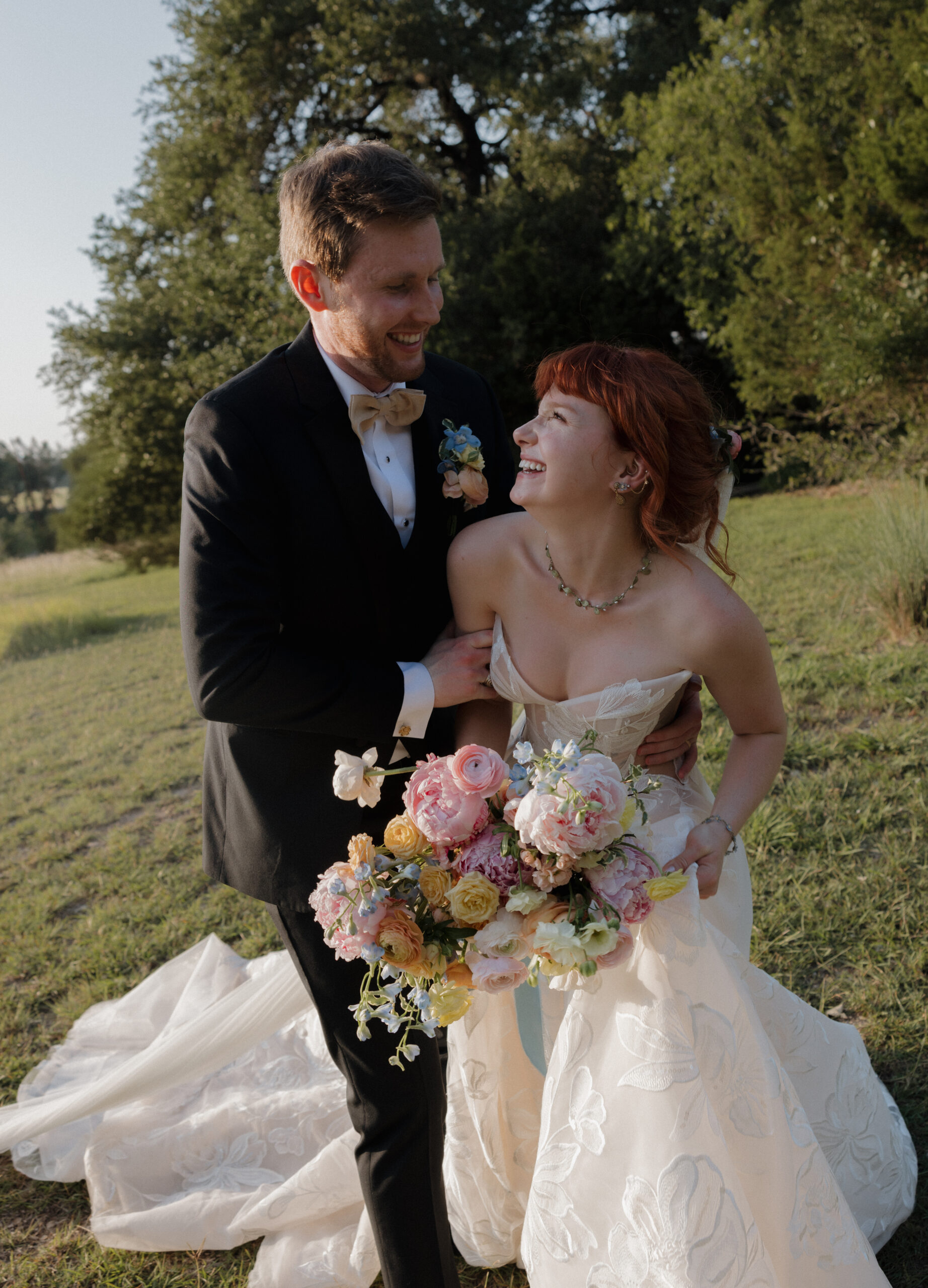 Bride and groom walking through oak trees at Camp Lucy in Austin, Texas during golden hour