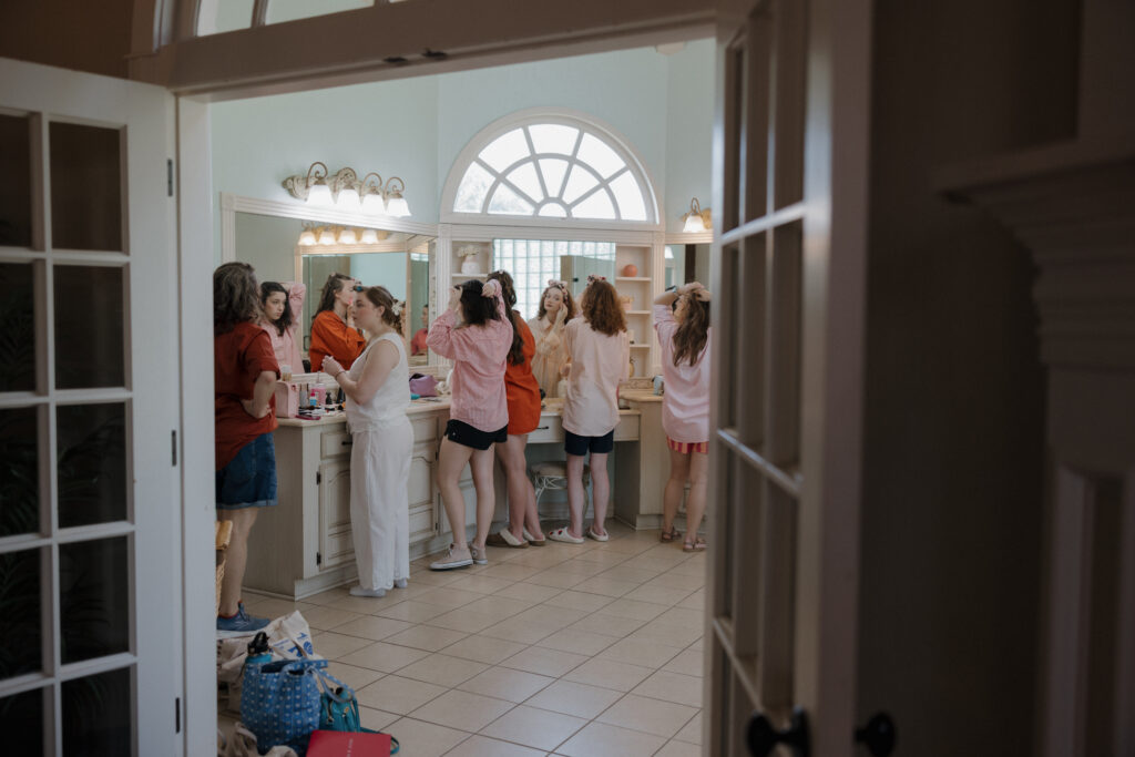 Bride and bridesmaids getting ready together in bright bridal suite at The Belle Manor, candid and documentary-style.