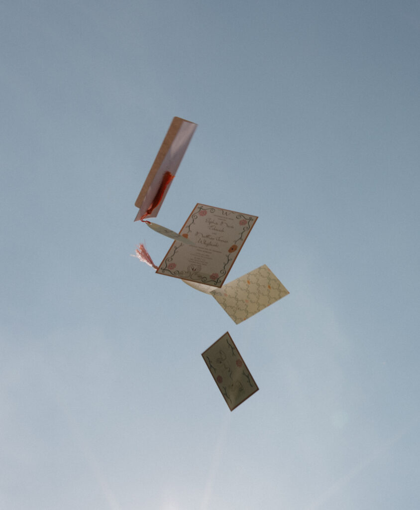 Creative photo of wedding invitations floating midair against clear blue sky — symbolic and playful design shot.